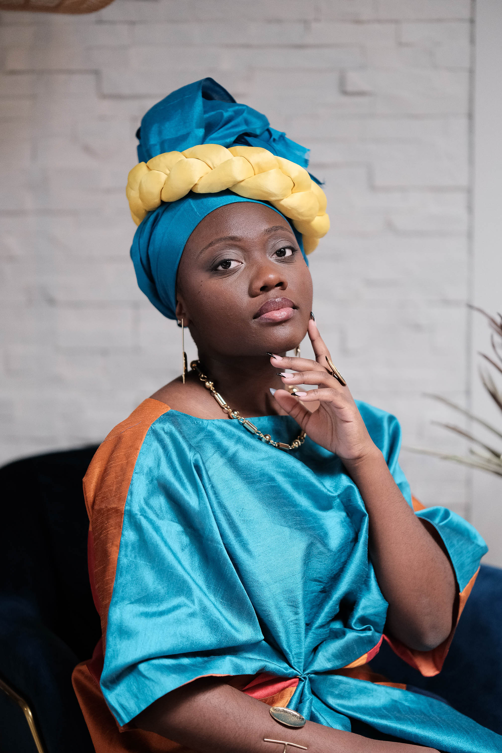 Marie-Paul Duwai-Sowa, award-winning poet and artist, wearing a teal headwrap and gold jewelry
